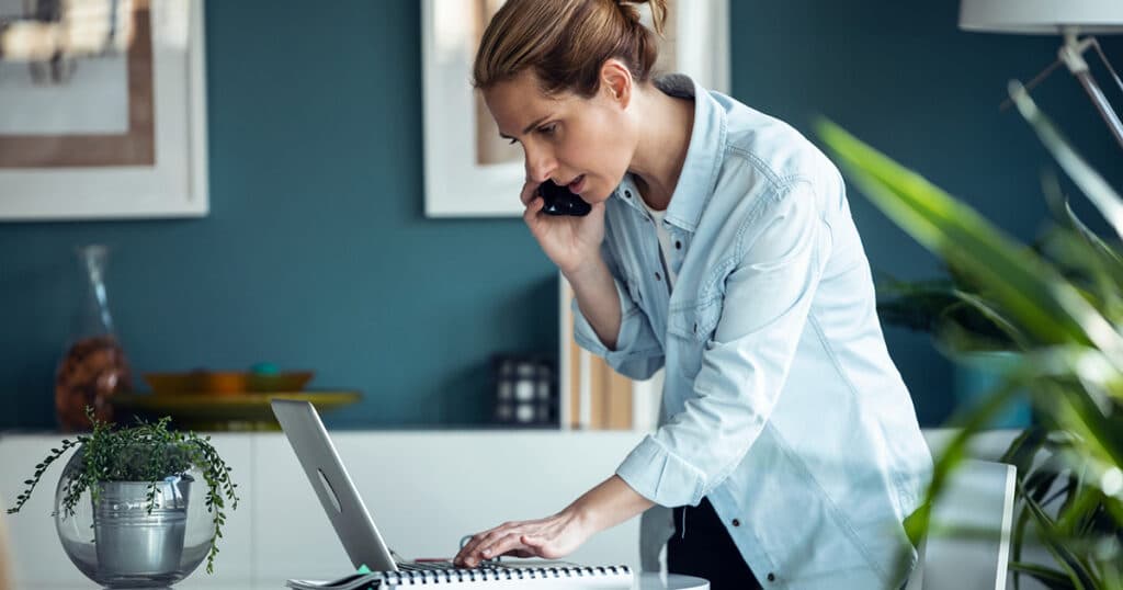 photo of woman concerned talking on the phone and looking at computer