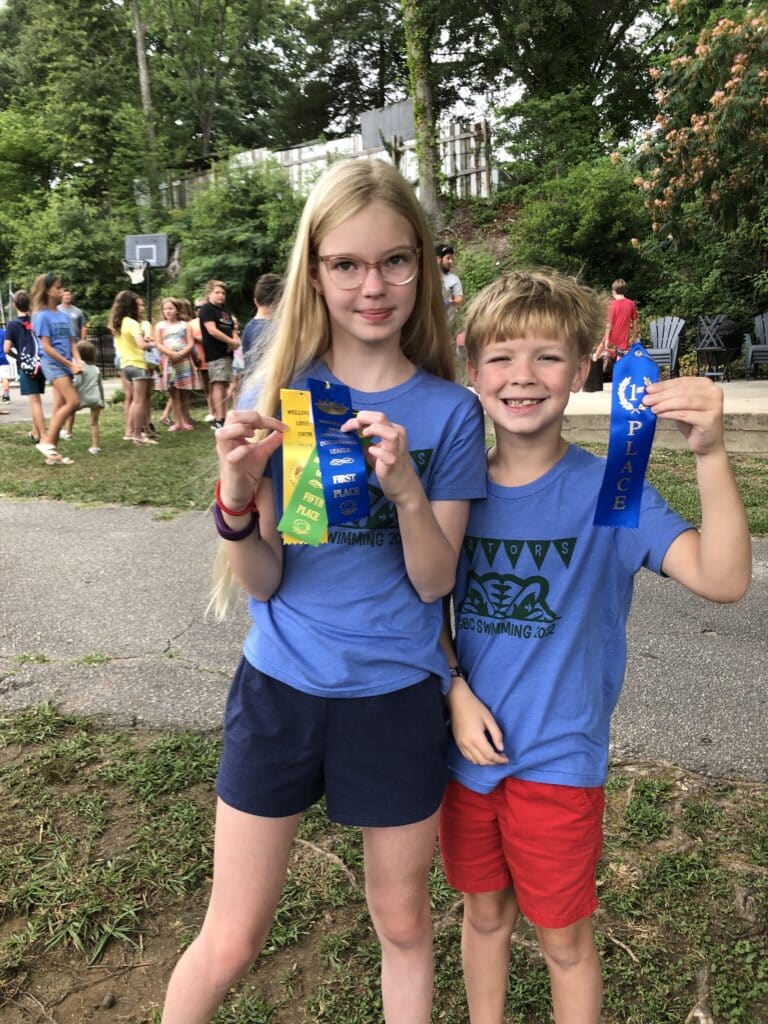 two kids holding up awards from swim class
